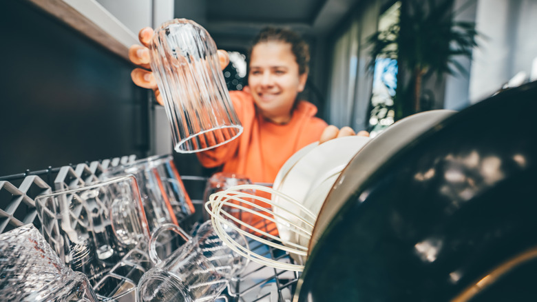 Woman happily loading dishwasher