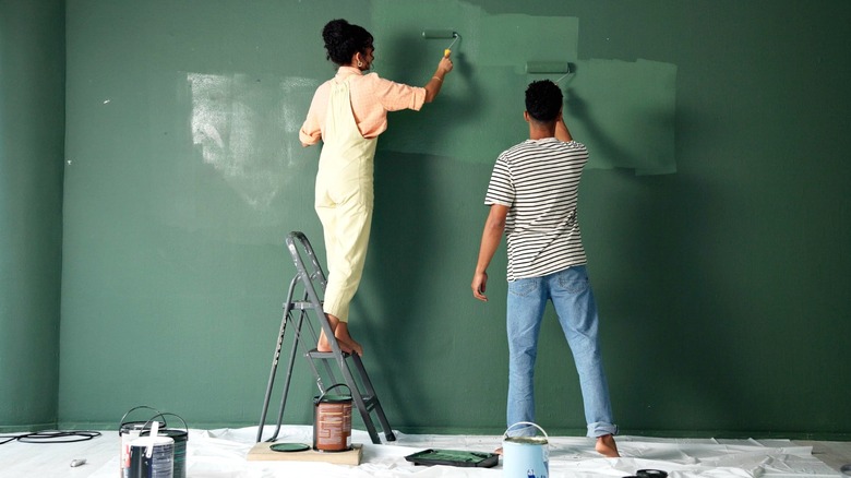 couple painting green wall with