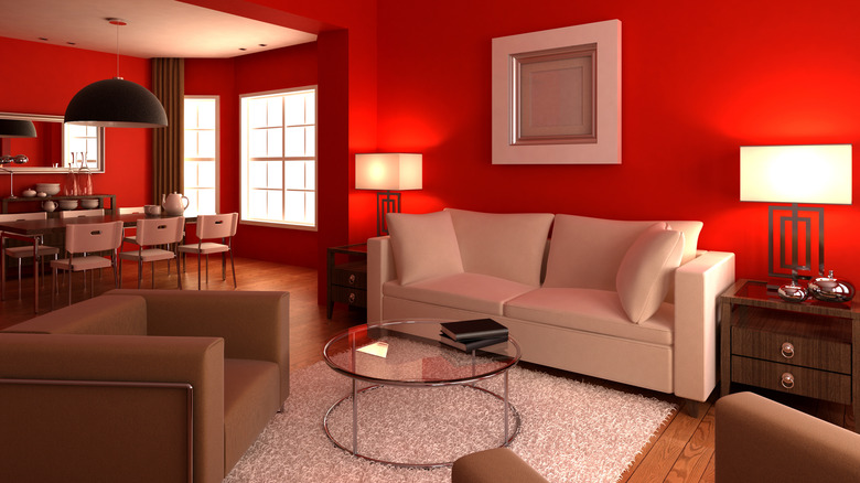 An open plan living area with red walls and neutral furniture