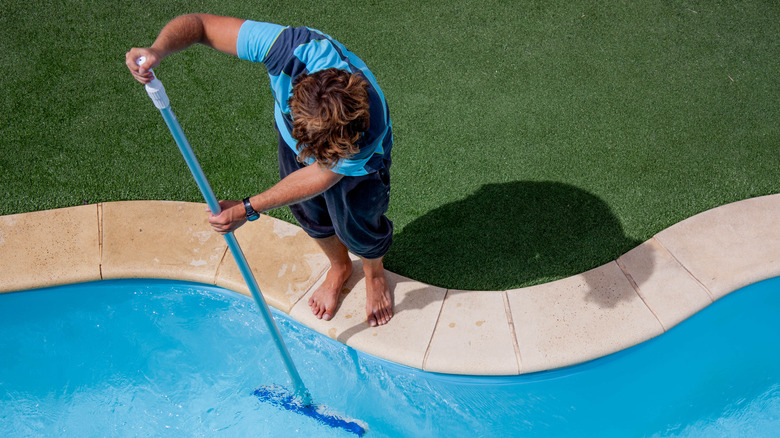 Man brushing the side of pool