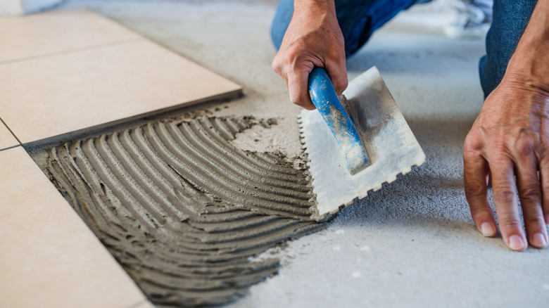 A man installing tiles on concrete