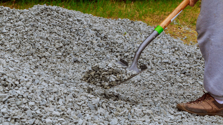 Person moving gray gravel with shovel