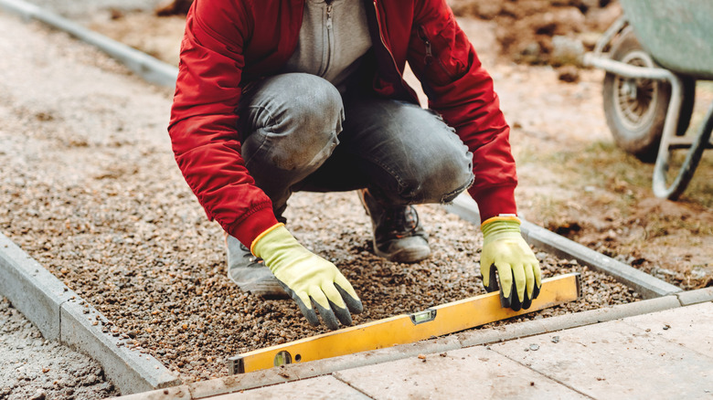 Worker checking concrete pavers with yellow level