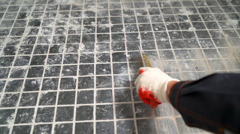 Person using a wire brush on grout lines