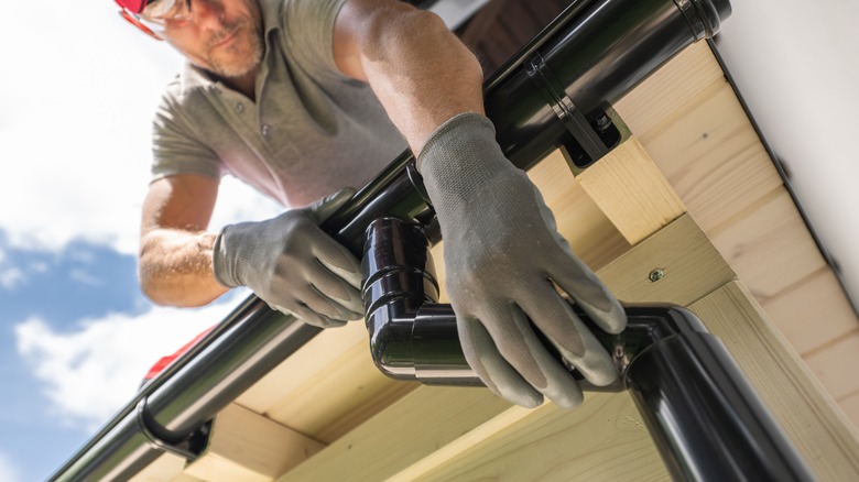 man installing gutters on a house