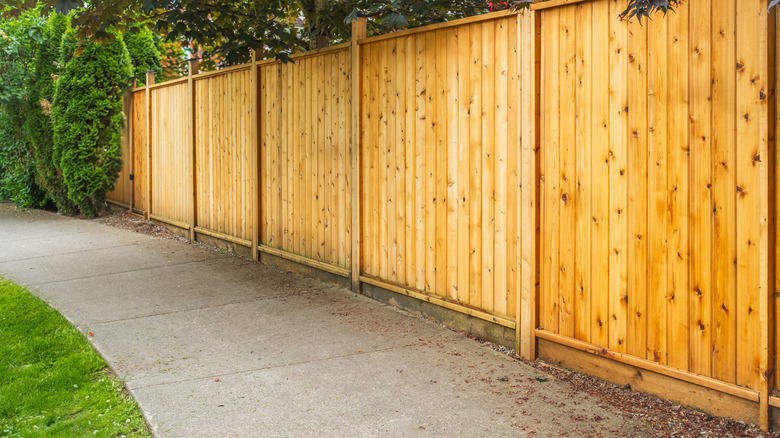 A red cedar fence bordering a sidewalk