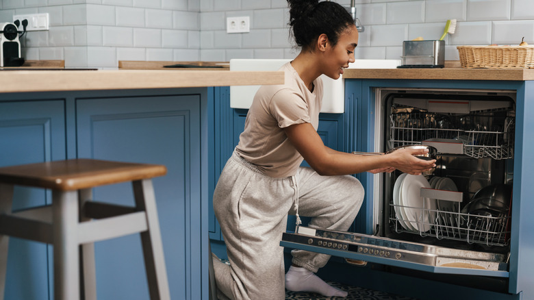 Woman using dishwasher