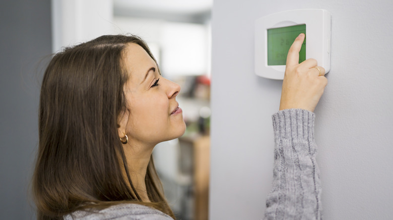 Person adjusting thermostat in home