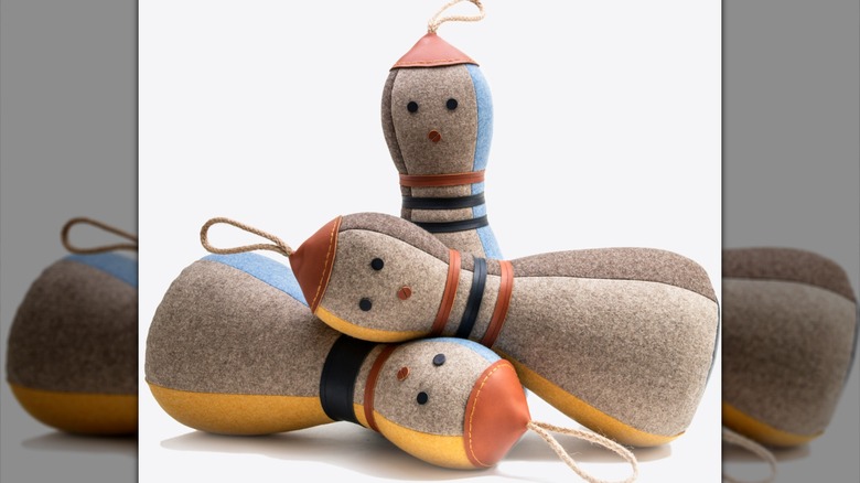 Black and white image of bowling pin felt doorstops in front of bookshelves