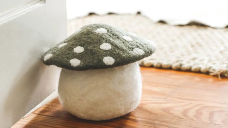 Green felted mushroom doorstop on wood floor