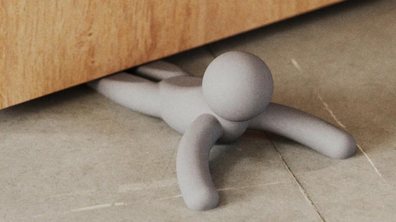 Plastic small man doorstop on floor under door