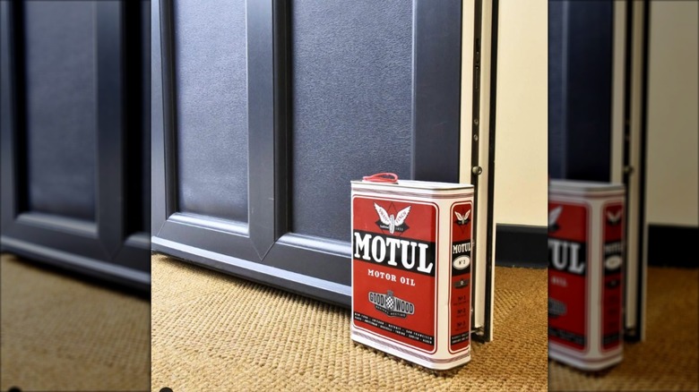 Red and black motor oil can doorstop in front of door