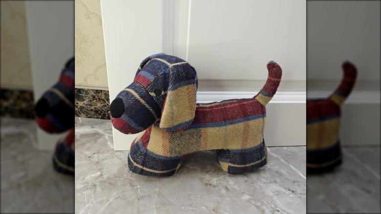 Plaid dog doorstop in red, yellow, and blue against door