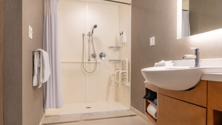 A neutral roll-in shower in a neutral bathroom.