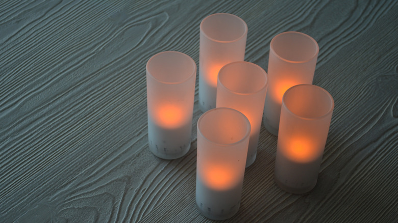 Six battery-operated candles flicker inside frosted glass jars.