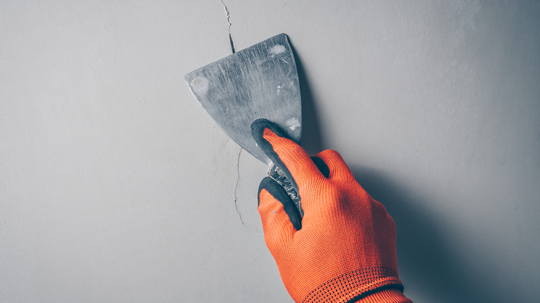 person sealing crack on wall