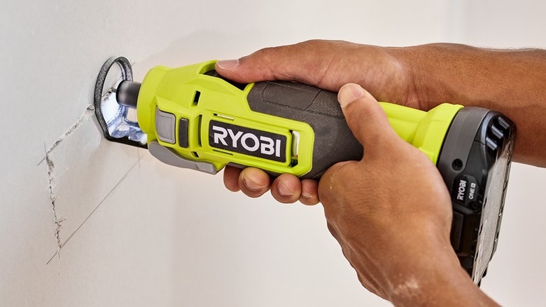 person cutting drywall with a rotary cutter