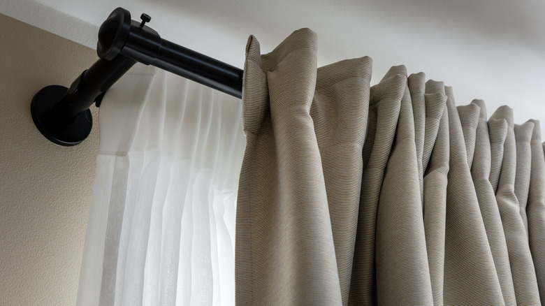 tan drapes hanging from thick black curtain rod