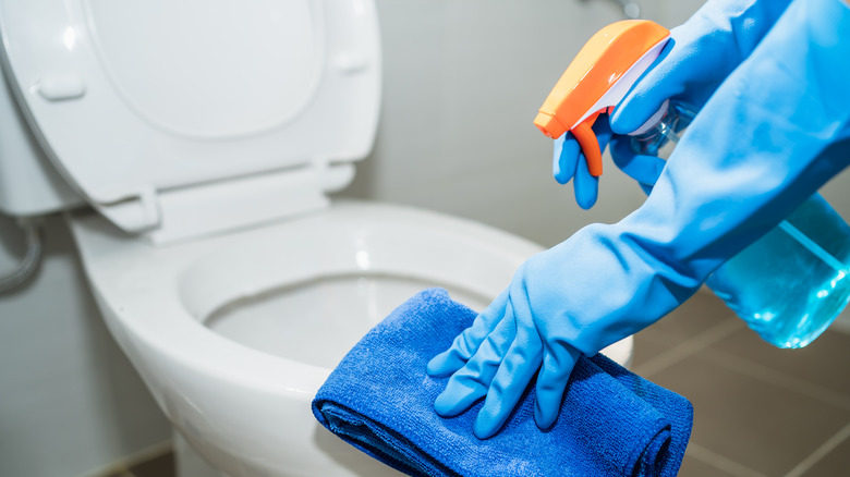 gloved hands cleaning toilet