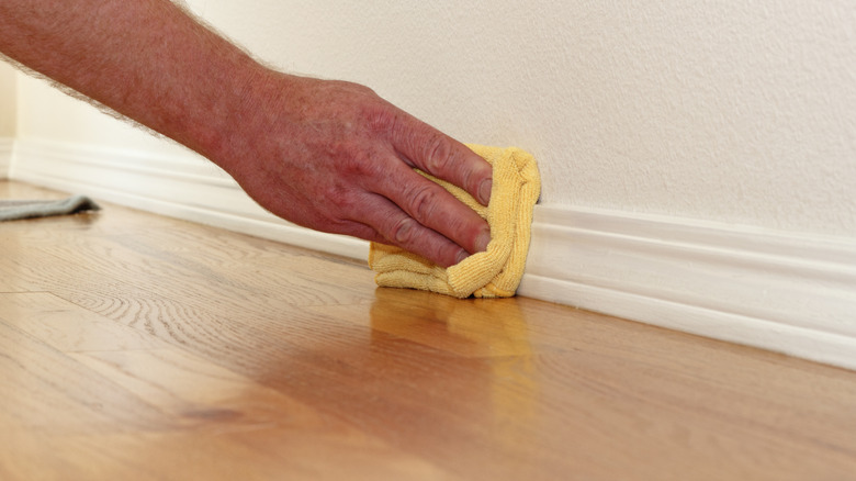 cleaning baseboard with rag