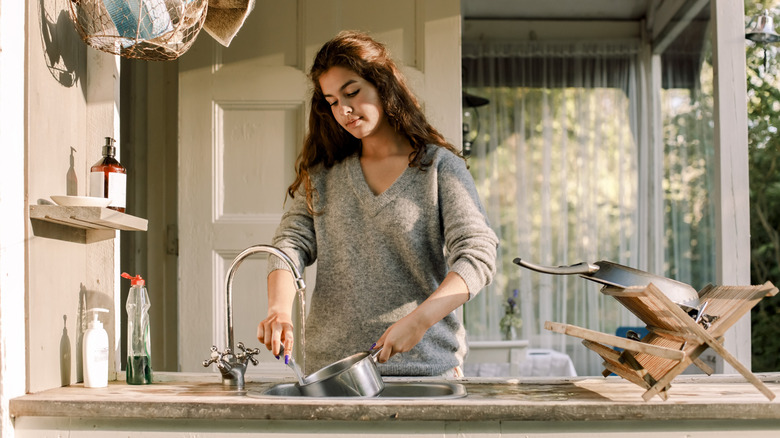 Woman washing pot in outdoor kitchen sink