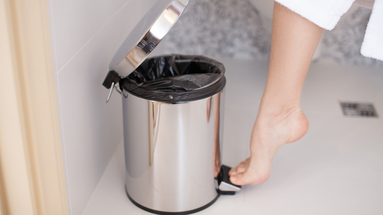 woman using bathroom trash can