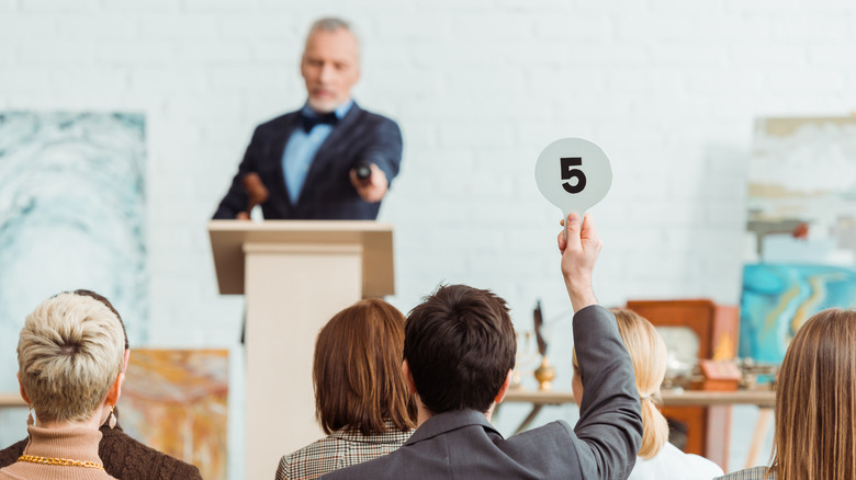 A man holding up a bid paddle