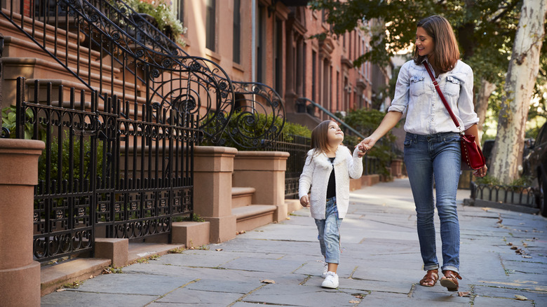 mother and daughter walking on sidewalk