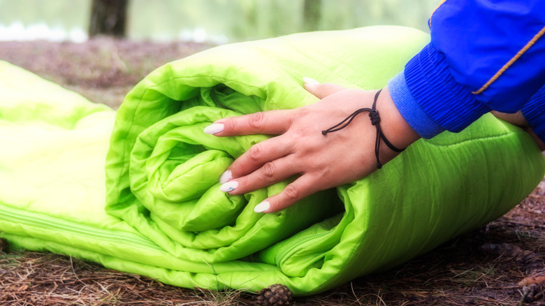 person rolling up sleeping bag