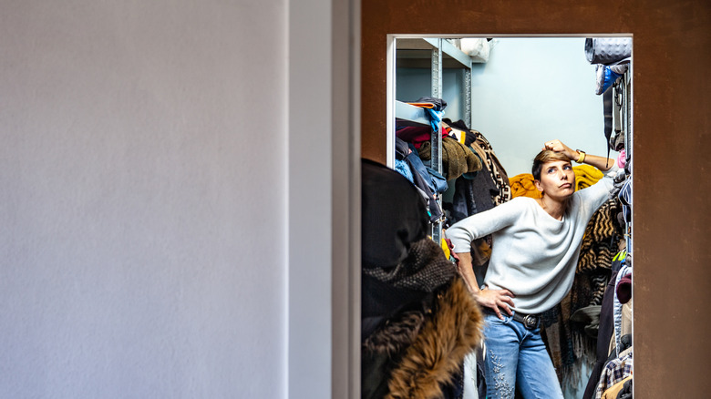 Annoyed woman in cluttered closet