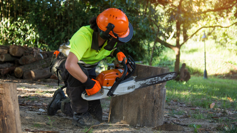 woman using chainsaw on stump