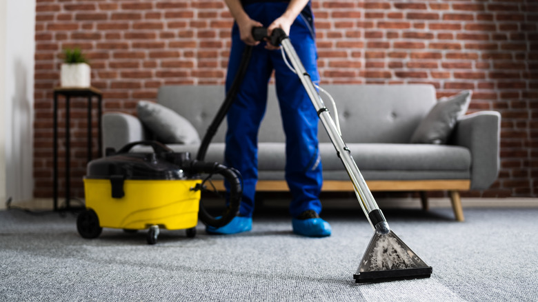 person cleaning carpet with vacuum 