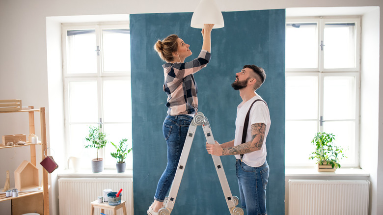 couple on ladder changing light