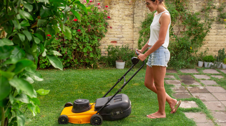 woman mowing backyard lawn