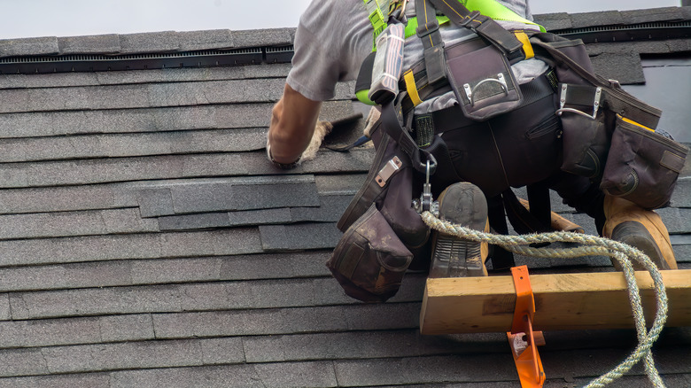 Person installing roofing shingles