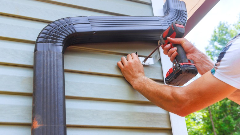 a man installing gutters and drainage pipes