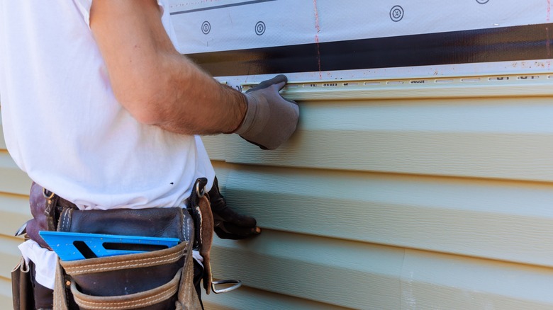 Person installing siding on a home