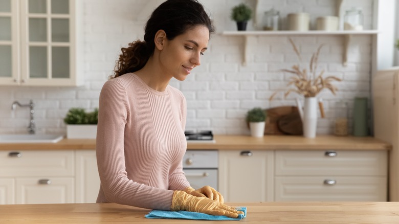 woman cleaning butcher block counter