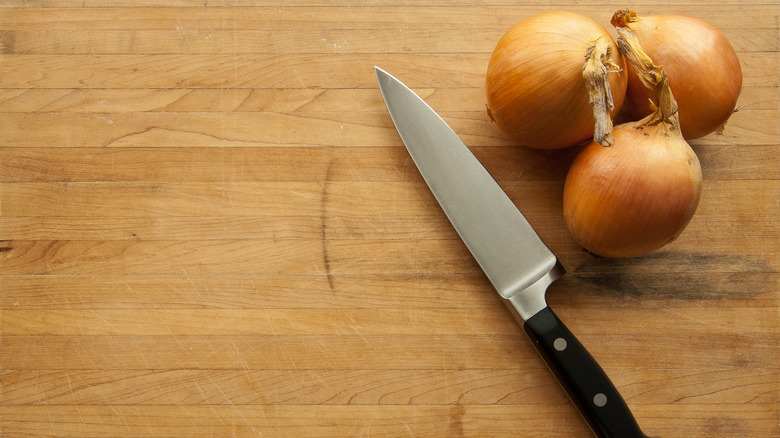 knife and onions on butcher block