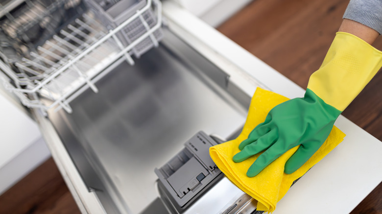 A person cleans inside the dishwasher