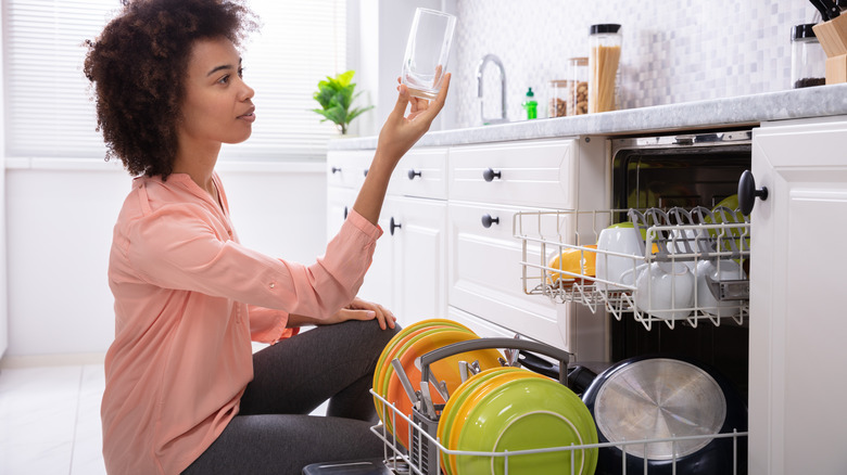 A woman checks dishes from the dishwasher