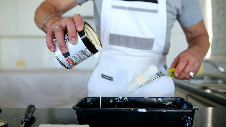 A man pouring paint in his kitchen