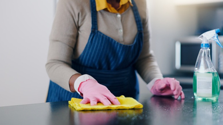 Woman wiping countertop with yellow cloth