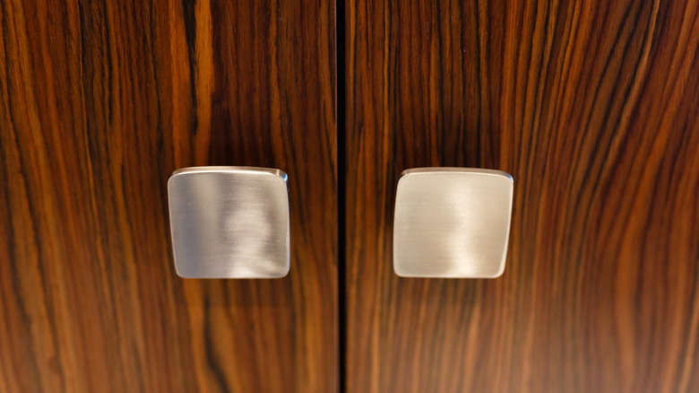 Two square cabinet knobs on a wooden cabinet