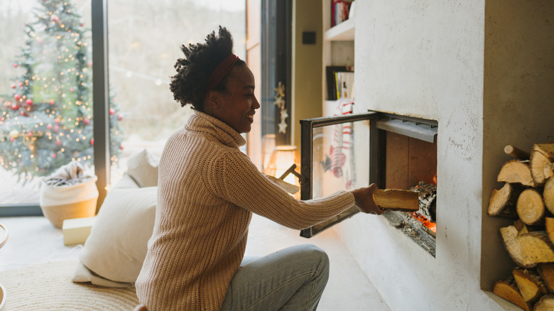 Woman adding log to fireplace