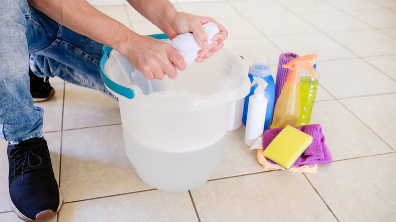 Man rings towel over bucket