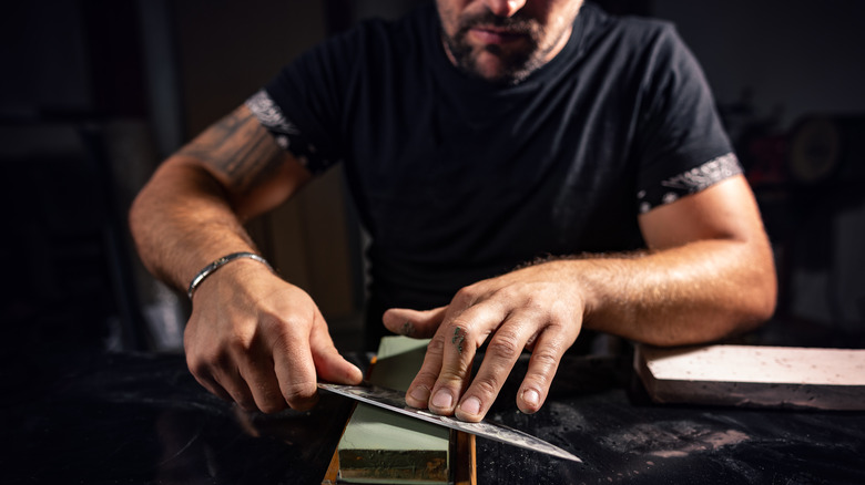 Man sharpening knife with whetstone