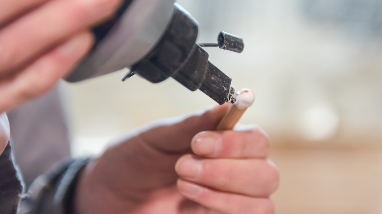 Hands applying glue to wood dowel