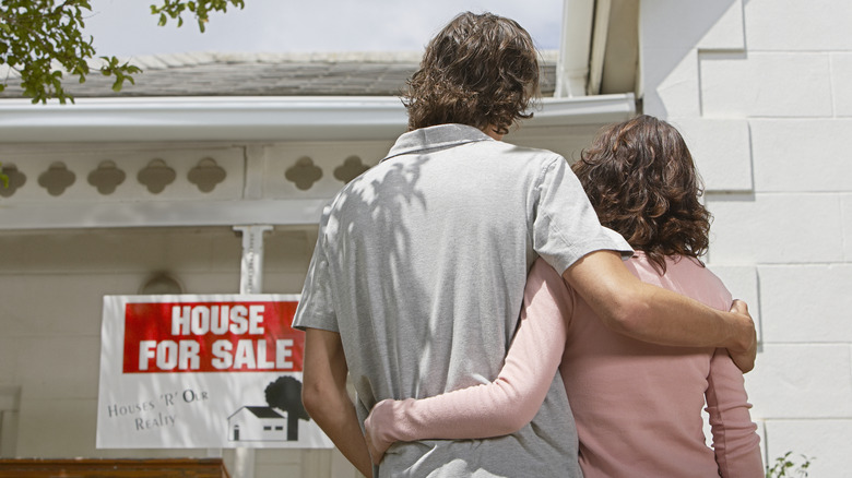 house for sale sign with couple