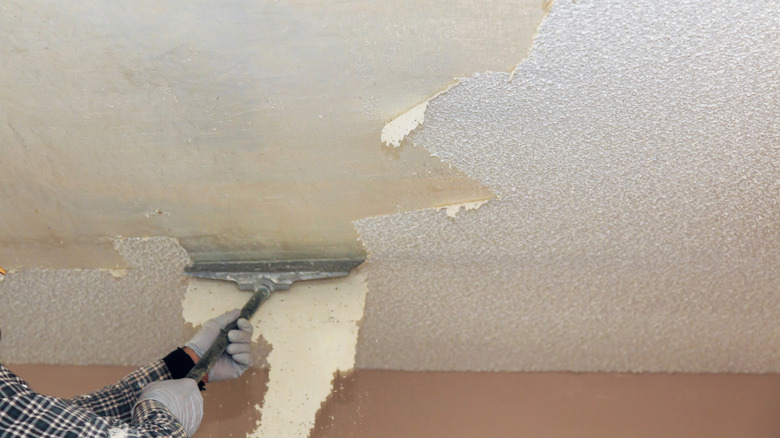 A person removes a popcorn ceiling